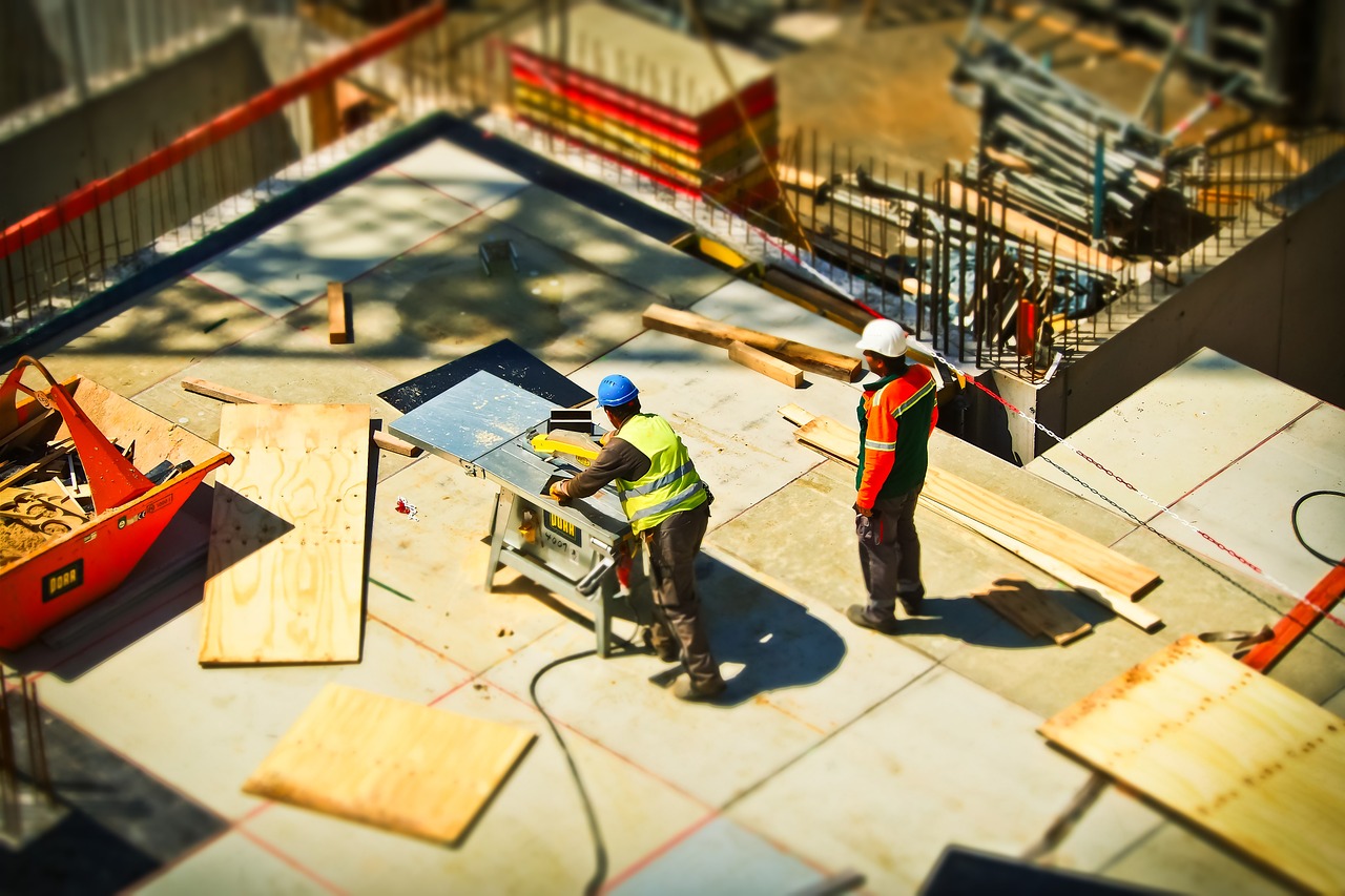 Zwei Männer arbeiten auf einer Baustelle. Dafür ist eine Einweisung an der Maschine nötig.